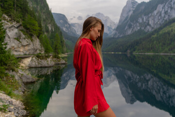 Beautiful girl in a red dress in the mountains near the lake