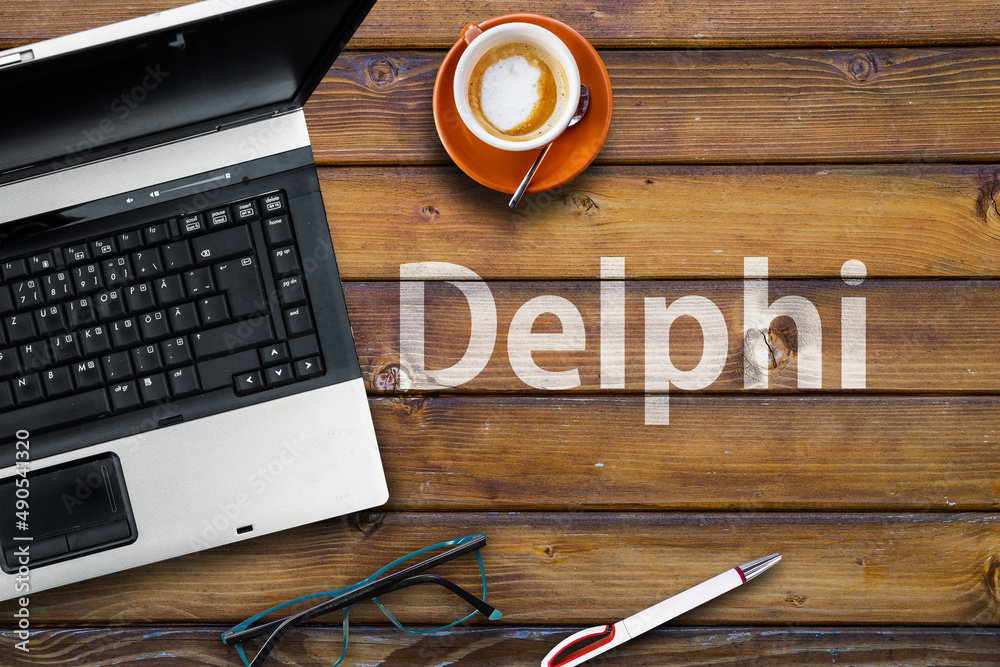 Poster delphi programming language. word delphi on wooden desk and laptop
