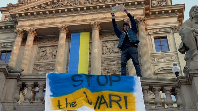 Man protesting against war in Ukraine on balustrade with flags, Prague.