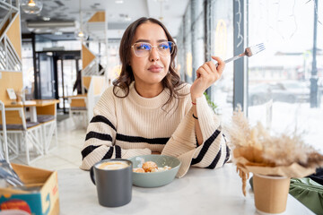 Cute young woman having a snack at lunch in a cafe, curd balls, freelancing