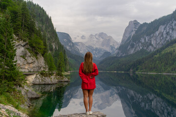 Naklejka premium Beautiful girl in a red dress in the mountains near the lake