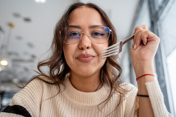 Close-up of the face of a cute young woman at lunch with a fork