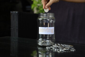 young man holding a coin putting it in a glass. the concept of saving money for financial accounting