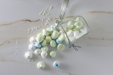 an open glass jar with colorful meringue sweets, spring concept, white, blue, pastel colors