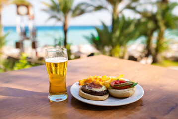 Delicious craft hamburger on a wooden plate in luxury hotel terrace with a sea view in summer time