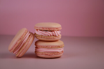 close up of pink macaroons with pink buttercream on pink background 