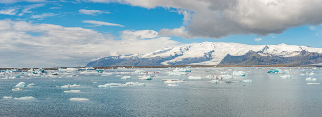 Panoramic view of Glacier Lagoon Jokulsarlon with icebergs and Vatnajokull Glacier tongue, Iceland, summer, with a touristic kayaking and people.