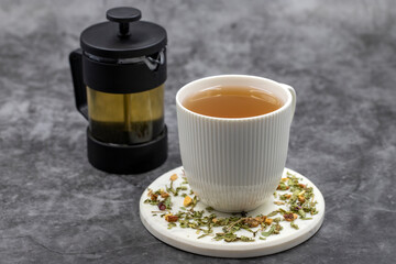 Fototapeta na wymiar Relax herbal tea on a dark background. Herbal tea prepared with lemon balm leaves, jasmine flower, apple peel, orange, lemon and hibiscus particles.