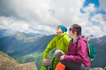 Young brave couple woman and man hiker sitting on the top of mountain