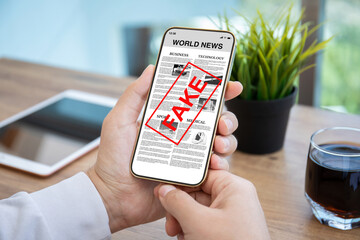 male hands hold phone with business news and word fake