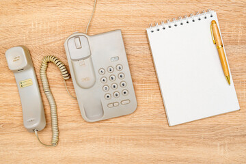 Vintage telephone and blank notebook on wooden background
