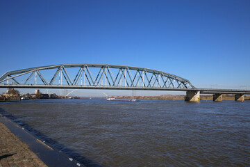 View on truss railway bridge over river waal against blue sky 