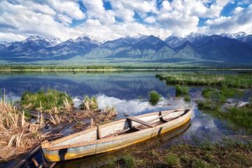 Landscape with mountains, lake and old wooden boat