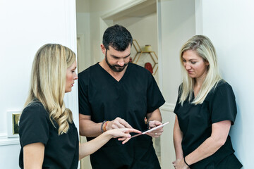 A male physician doctor at a medical spa and wellness clinic speaking to two female nurse practitioners