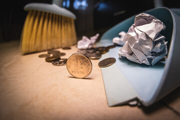 Coins on the background of a scoop and a broom for cleaning