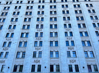 Fototapeta premium A lot of windows at the building elevation. Brick office building. Facade. Brick elevation. Stone. Variety. Multiple windows. Architecture. Rows. Massive