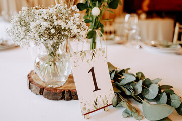 Number One Paper List and Flower in Vase on Table Closeup Photography. Natural Aromatic Bouquet in Glass on Wooden Stand, Green Leaves Branches and Nameplate on Restaurant Dinning Desk