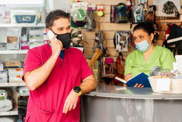 Veterinary clinic staff and pet shop, answering a client by phone and scheduling a date for...