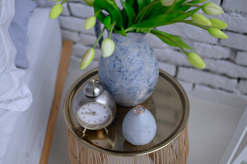 Wedding rings on a nightstand with a clock and a vase.
