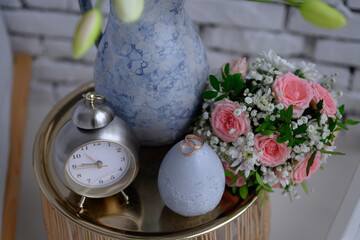 Wedding rings on a nightstand with a clock and a vase.

