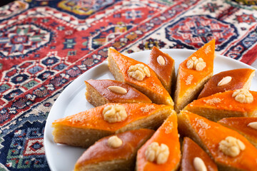 Plate of Azerbaijani national pastries for Novruz pakhlava and shakarbura on ethnic rug or carpet for Novruz, spring equinox and new year celebration in March. Copy space  