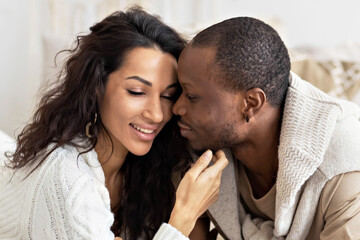 A couple in love - a black man and a woman on a bed in a bright room. Diverse family
