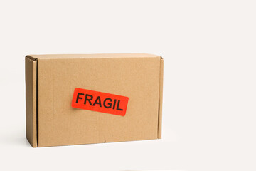 Caja de cartón con pegatina fragil sobre un fondo blanco liso y aislado. Vista de frente y de cerca. Copy space