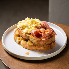 Obraz na płótnie Canvas Toast with fried bananas, bacon, scrambled eggs and maple syrup