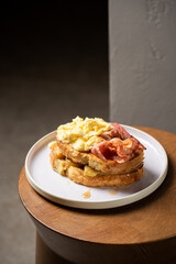 Toast with fried bananas, bacon, scrambled eggs and maple syrup