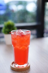 Refreshing cold beverage for summer on ice. Colorful summer drink in tall glass with wood saucer for hot day and party.