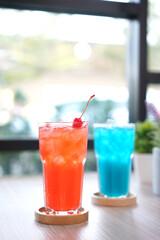 Refreshing cold beverage for summer on ice. Colorful summer drink in tall glass with wood saucer for hot day and party.