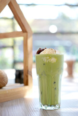 Green tea with milk or latte match with vanilla ice cream in cafe. Fresh and dessert in tall glass.