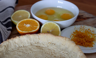 Making orange pie. Close up photo of fresh ingredients. Crusty dough, oranges, sugar, eggs top view photo. 