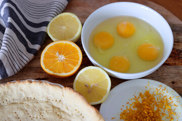 Making orange pie. Close up photo of fresh ingredients. Crusty dough, oranges, sugar, eggs top view photo. 