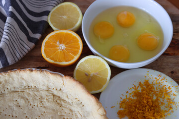 Making orange pie. Close up photo of fresh ingredients. Crusty dough, oranges, sugar, eggs top view photo. 
