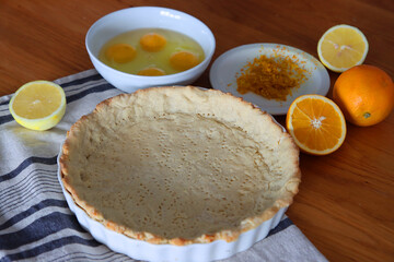 Making orange pie. Close up photo of fresh ingredients. Crusty dough, oranges, sugar, eggs top view photo. 