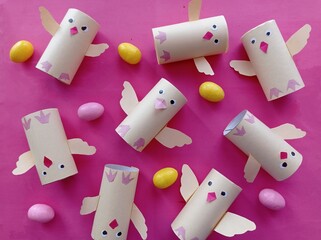homemade toy chickens and painted easter eggs on a pink background