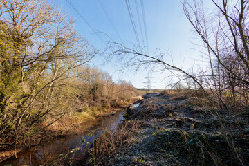 11th Feb 2022: Tyne Riverside Country Park on a sunny winter morning with stream and electricty pylons