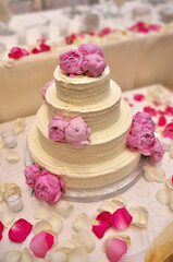 Obraz na płótnie Canvas An Elegant Tiered Buttercream Wedding Cake Decorated with Peonies 