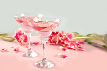 Glasses of pink cocktail with flowers and petals. Birthday party or Valentines day romatic couple concept.