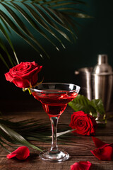 Delicious refreshing beverage drink red cocktail with red rose and petals on wooden table. Romantic, Valentines day concept.