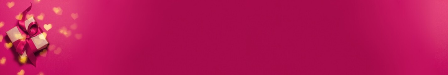 Banner of brown paper gift box with a magenta satin ribbon bow on pink background with gold bokeh of heart shapes with copy space. Flat lay Valentines day father mother day and presents concept
