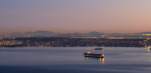 Obraz premium Panoramic View of Burrard Inlet and Cityscape. Modern City on Pacific Ocean West Coast. Winter Sunset. British Columbia, Canada.