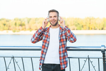happy handsome unshaven man in checkered shirt listen music in headphones outdoor, music