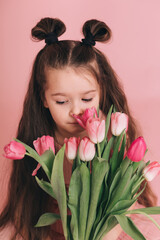Portrait of a girl with tulips on pink background.