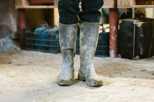 Crop farmer in dirty rubber boots standing in barn
