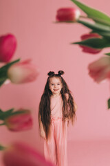 Obraz na płótnie Canvas Portrait of a girl with tulips on pink background.