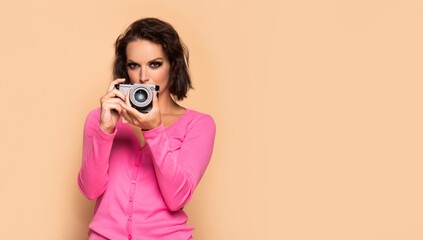 Serious girl photographing with photo camera beige background copy space, photographer