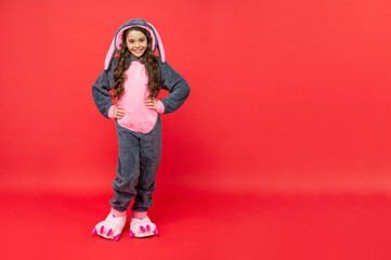 happy kid in comfortable pajama on red background with copy space, full length, bedtime