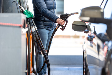 High prices of petrol and diesel fuel ath the petrol station, young woman refueling the car,...